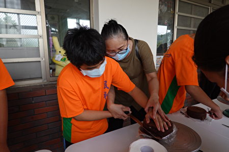  春晖志工手把手，辅导民和国中慈辉分校学生将蛋糕切半。