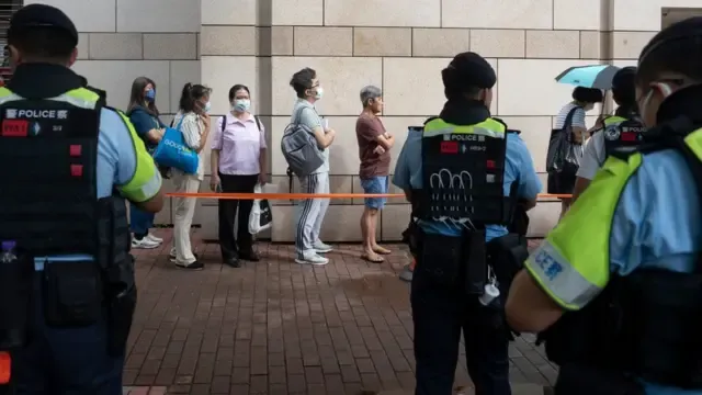 中国香港特区西九龙裁判法院外旁听“47人案”民众在警察面前排队等候（25/6/2024）