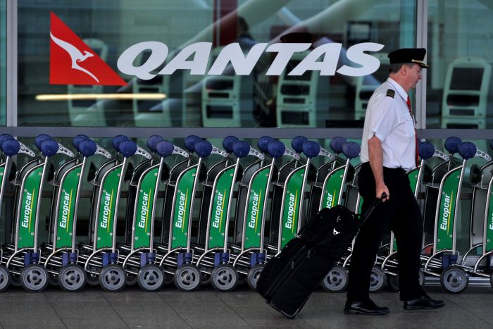 Pilot walks past Qantas sign at Sydney airport