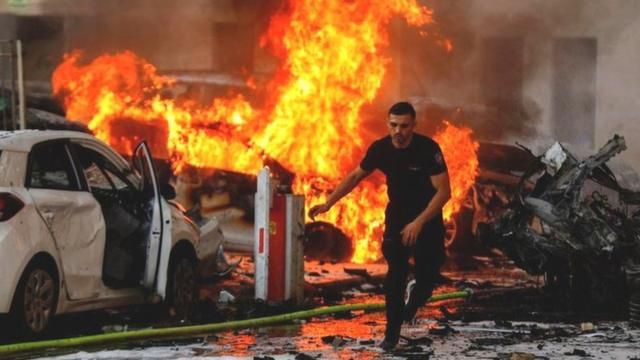 A man runs on a road as fire burns after rockets were launched from the Gaza Strip, in Ashkelon, Israel October 7, 2023.