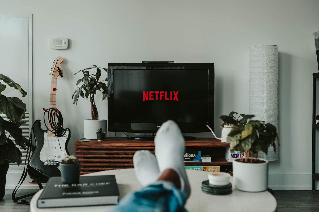 Image of a person watching Netflix on their couch, with their feet propped up on the coffee table