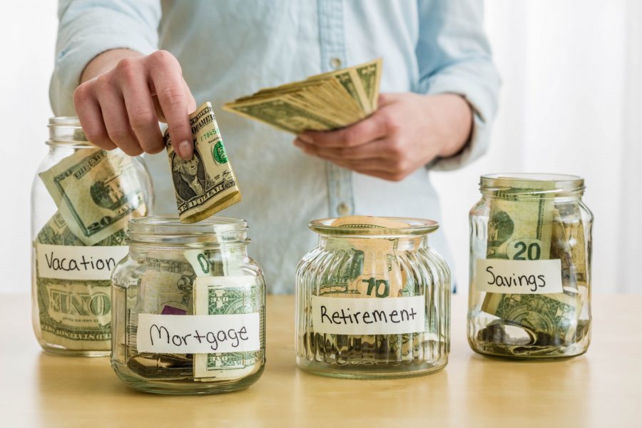 Image of someone putting money into jars to represent savings.