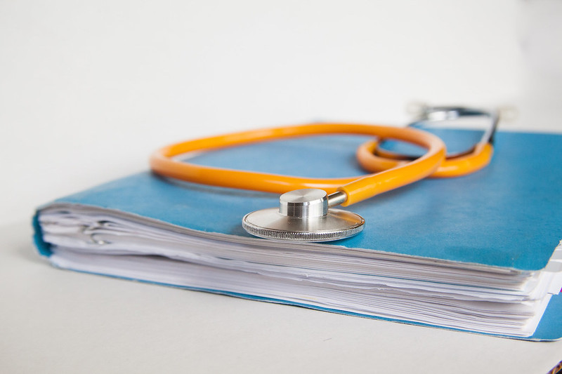 Blue folder of medical records with orange stethoscope laid on top