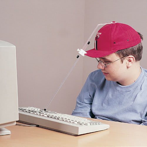 Person with a motor impairment wears a pointer cap to type on the keyboard, this allows him to use a computer