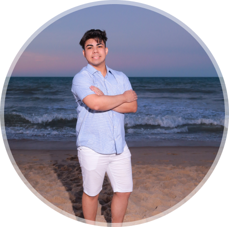 Foto do Pedro Euzebio sorrindo com braços cruzados numa praia com no fundo o mar