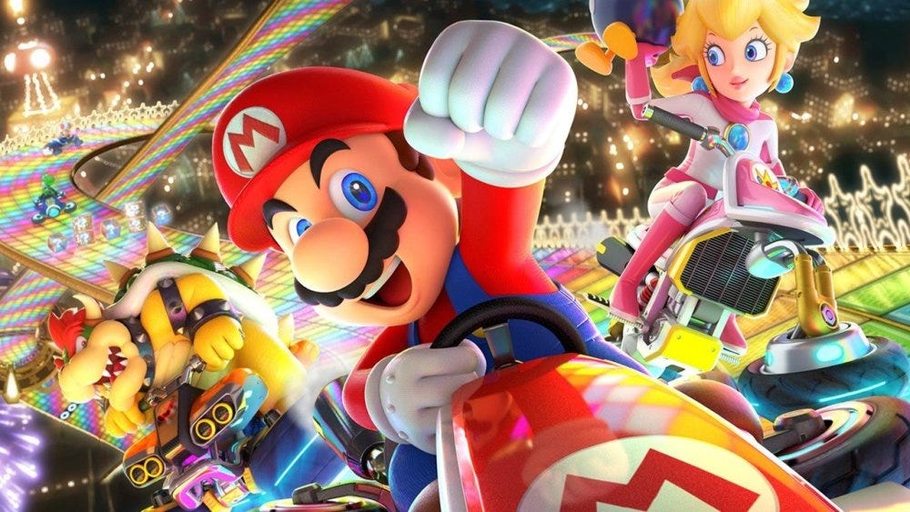 Background splash art for Mario Kart, highlighting Mario driving a small kart in front of Peach and Bowser also driving karts on a rainbow-colored racetrack