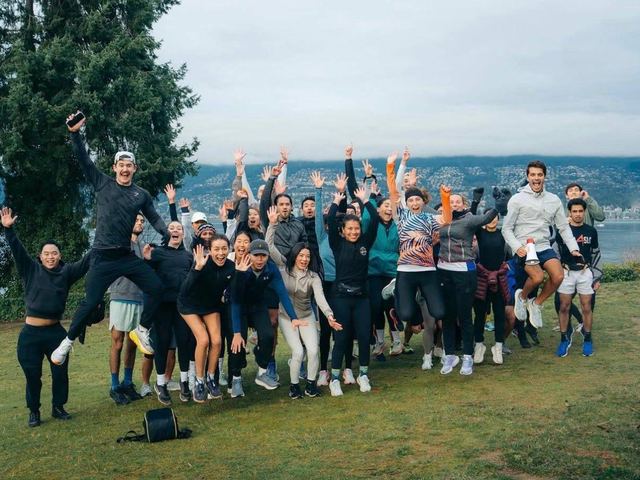 Run club jumping for a photo by the water