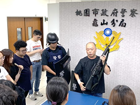 警察工作环境让学习结合实务，员警展示警用装备长短枪、防弹衣、盾牌及拘留所，让大学生体验。