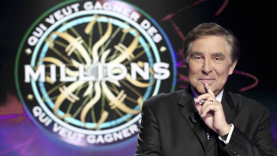 Jean-Pierre Foucault devant le logo du jeu Qui veut gagner des millions ?