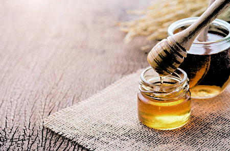 Honey with wooden honey dipper on wooden table