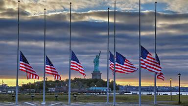 Statue of Liberty seen behind US flags at half-staff for the anniversary of September 11 in 2014, New York City (© Adam Parent/Shutterstock)