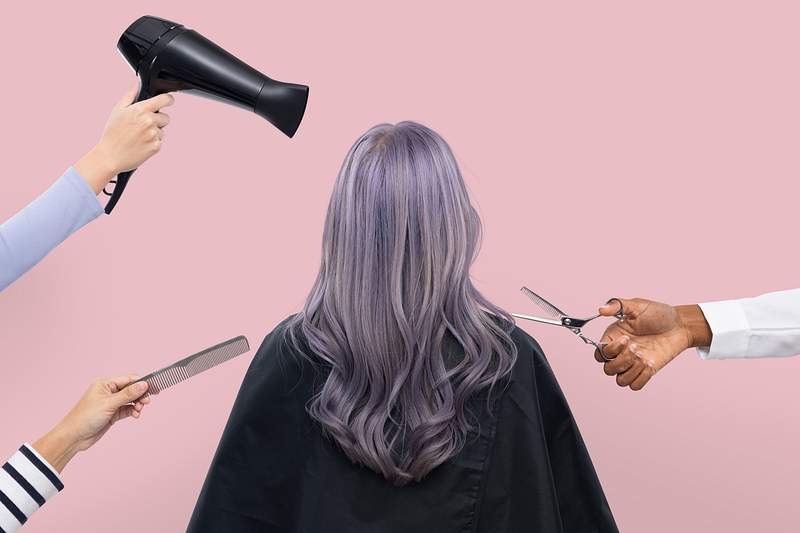 Picture of the back of a person with long lavendar hair in front of a pink background. Three hands surround the persons head holding various tools you would find in a hair salon.