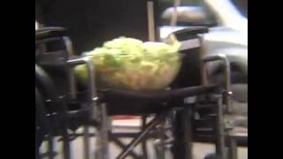 A bowl of salad in the seat of a wheelchair rolling down the street unassisted  with Diana Ross 
